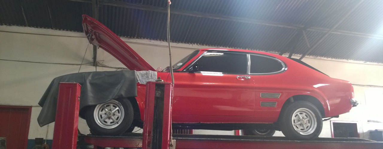 red sports car standing on hydraulic lift with the engine being worked on by xxx